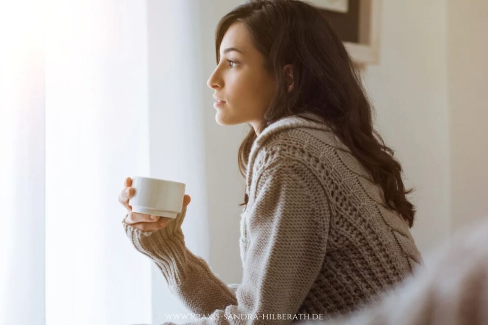 Nachdenkliche Frau am Fenster – negative Gefühle verstehen und einen neuen Umgang mit Emotionen finden
